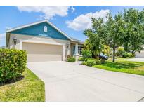 Charming single-story home featuring a two-car garage, blue accents, and meticulously maintained landscaping at 11790 Fennemore Way, Parrish, FL 34219