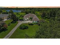Stunning lakefront home featuring lush landscaping and a sprawling green lawn with a circular driveway at 22354 Panther Loop, Bradenton, FL 34202