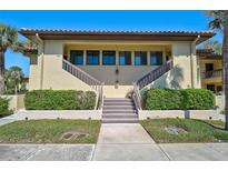Inviting two-story condo with lush landscaping, stairs leading to front doors, and tropical palm trees at 5201 Lake Village Dr # 14, Sarasota, FL 34235