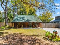 Charming log cabin with inviting front porch, green roof, and natural wood finishes at 6811 6Th W St, Bradenton, FL 34207