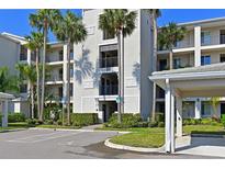 Condo exterior features covered parking, well-manicured landscaping, and several palm trees on a sunny day at 910 Tidewater Shores Loop # 107, Bradenton, FL 34208