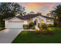 Beautiful home exterior showcasing a manicured lawn, arched windows, and tiled roof at sunset at 9408 Glen Abbey Ln, Sarasota, FL 34238
