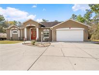 Exterior view of a single-story home with a well-manicured lawn and a two-car garage at 13040 Quigley Ave, Weeki Wachee, FL 34614