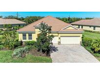Charming yellow single-story home with a brick driveway, well-maintained landscaping, and a tile roof at 428 Grand Preserve Cv, Bradenton, FL 34212