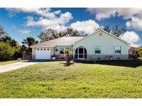 Charming single story home featuring a lush front lawn, attached garage, and arched entryway at 4360 Flamingo Blvd, Port Charlotte, FL 33948