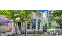 Charming home featuring arched windows and a quaint patio, framed by lush palm trees for a tropical feel at 446 Burns Ct, Sarasota, FL 34236
