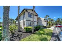 Two-story condo with neutral stucco, trimmed windows, mature landscaping, and dedicated parking at 5630 Golf Pointe Dr # 205, Sarasota, FL 34243