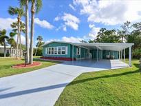 Charming home featuring a covered carport, well-manicured lawn, and vibrant landscaping at 5910 Majestic Way, Palmetto, FL 34221
