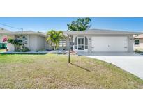 Charming single-story home featuring a manicured lawn, well-maintained landscaping, and an attached two-car garage at 6387 Shalimar St, Port Charlotte, FL 33981