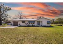 Charming single story home with a well-manicured lawn and a metal roof, set against a backdrop of a vibrant sunset at 7150 Richardson Rd, Sarasota, FL 34240