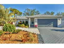 Charming single-story home featuring a metal roof, lovely landscaping, and a gray brick driveway at 7612 4Th Avenue Nw Dr, Bradenton, FL 34209