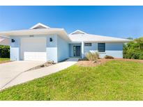 Charming single-story home with a well-manicured lawn and attached garage, painted in a lovely light blue hue at 3910 Cape Haze Dr, Rotonda West, FL 33947