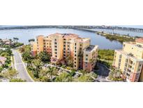 Beautiful multi-story condo building with barrel tile roof, tropical landscaping, and water views at 615 Riviera Dunes Way # 208, Palmetto, FL 34221