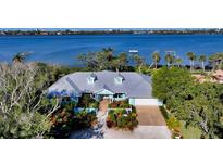 Stunning waterfront home with lush landscaping, brick driveway, and elegant architecture at 1440 Kimlira Ln, Sarasota, FL 34231