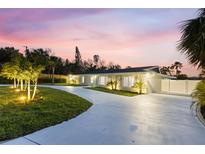 Beautifully landscaped home featuring a long driveway with elegant exterior lighting at dusk at 4646 Gleason Ave, Sarasota, FL 34242
