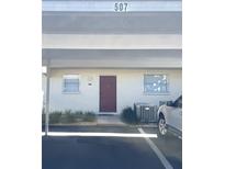 Exterior of condo featuring covered parking, a red door, and minimal landscaping at 507 Parkdale Mews # 507, Venice, FL 34285