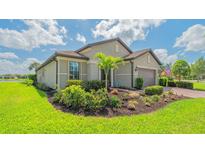 Beautifully landscaped front yard with a well-maintained lawn, palm tree, and colorful flowerbeds at 5562 Rain Lily Ct, Sarasota, FL 34238