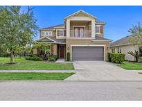 Two-story tan home with a two-car garage, front porch, second story balcony, and manicured lawn at 5954 Anise Dr, Sarasota, FL 34238
