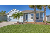 Charming single-story home with blue exterior, well-manicured lawn, and palm trees. Garage at 6105 114Th E Dr, Parrish, FL 34219