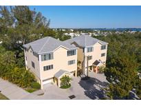 Bright and airy two-story home featuring a gray roof and well-manicured landscaping at 660 Cedars Ct, Longboat Key, FL 34228