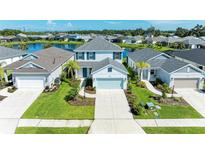 Overhead view of a charming two-story home with a well-manicured lawn and a serene lake backdrop at 10614 Morning Marsh Ln, Parrish, FL 34219