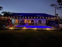 A beautiful screened-in pool and outdoor space is lit up at dusk at 145 Baytree Dr, Rotonda West, FL 33947