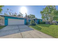 Charming single-story home with a two-car garage, lush lawn, and vibrant turquoise exterior at 2261 Linwood Dr, Sarasota, FL 34232