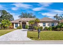 Charming single-story home featuring a meticulously landscaped front yard and beautiful brick driveway at 2439 Sonoma W Dr, Nokomis, FL 34275