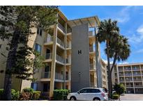 A condo building showcasing multiple balconies with beautiful palm trees and landscaped foliage around the property at 3719 Lake Bayshore Dr # H-204, Bradenton, FL 34205