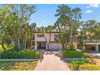 Charming two-story home with tropical landscaping and a brick-paved driveway leading to a two-car garage at 4002 6Th Ave, Holmes Beach, FL 34217