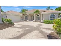 Charming home featuring a tiled roof, arched windows, columns, palm trees, and a paver driveway at 5354 Nathaniel Pl, Sarasota, FL 34233