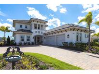 Elegant two-story home featuring a paver driveway, three-car garage, and lush landscaping at 8265 Pavia Way, Bradenton, FL 34202