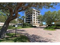 Inviting condo building featuring lush landscaping, brick drive, and mature trees on a sunny day at 8735 Midnight Pass Rd # 301B, Sarasota, FL 34242