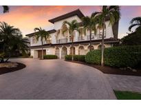 Elegant two-story home featuring stucco siding, a tile roof, arched entryways, and lush palm trees at 875 Siesta Key Cir, Sarasota, FL 34242
