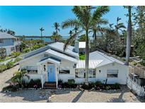 Charming waterfront home with vibrant blue door, lush landscaping, and glimpses of the ocean at 12204 45Th Avenue W Dr, Cortez, FL 34215