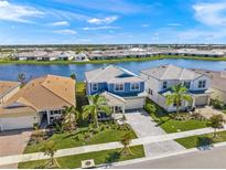 Beautiful aerial view of homes with lake views, tropical landscaping, and paver driveways in a well maintained community at 17966 Grand Prosperity Dr, Venice, FL 34293