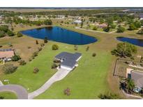 Expansive aerial view of single-story home featuring a private pond, lush green lawn, and long concrete driveway at 4606 Lake Fox Pl, Parrish, FL 34219