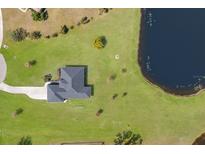 An aerial view shows this home's placement on a grassy lawn next to a dark lake with a winding driveway at 4606 Lake Fox Pl, Parrish, FL 34219