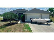 Charming single-story home featuring a two-car garage and a boat parked in the driveway at 4606 Lake Fox Pl, Parrish, FL 34219