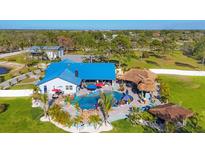 Stunning aerial view showcasing a custom home with a blue roof, luxurious pool area, tiki bar, and beautiful landscaping at 9902 284Th St E E St, Myakka City, FL 34251