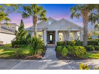 Charming single-story home featuring lush landscaping, a brick pathway, and a welcoming covered porch at 11717 Blue Hill Trl, Lakewood Ranch, FL 34211
