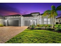 Elegant stucco home featuring a tile roof, three-car garage, and lush landscaping, offering curb appeal at 17916 Northwood Pl, Lakewood Ranch, FL 34202