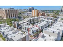 Modern townhomes showcase architectural design amidst a bustling cityscape, complemented by verdant trees at 232 Cosmopolitan Ct, Sarasota, FL 34236