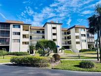 Multi-story condo building featuring lush landscaping, balconies, and a bright blue sky at 3630 Gulf Of Mexico Dr # 304, Longboat Key, FL 34228