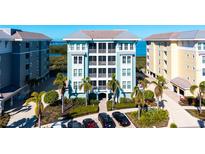 Beautiful coastal condo building featuring tropical landscaping, covered parking, and a water view at 388 Aruba Cir # 201, Bradenton, FL 34209