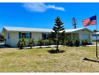 Charming single-story home with a metal roof, manicured landscaping, and American flag at 41 Young Ave, Englewood, FL 34223