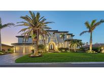 Elegant home with a lush lawn, mature palms, and a two-car garage showcased at dusk at 551 Ranger Ln, Longboat Key, FL 34228