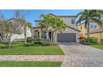 Charming two-story home with well-manicured lawn, lush landscaping, and a brick-paved driveway at 5723 Title Row Dr, Bradenton, FL 34210