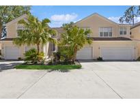 Light yellow townhome with attached garages, palm trees, and small landscaped garden at 6412 Rosefinch Ct # 102, Lakewood Ranch, FL 34202