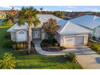 Charming home exterior boasts a lush lawn, beautiful landscaping, and a white tile roof at 664 Silk Oak Dr, Venice, FL 34293